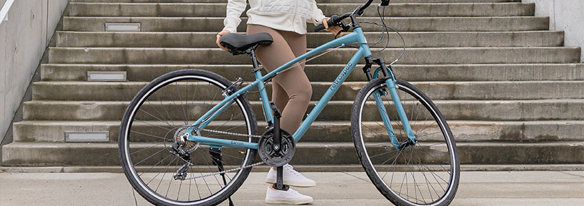 Girl standing behind blue Retrospec Barron Bike in front of concrete staircase