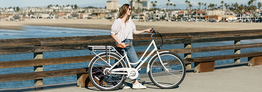 Girl standing behind Retrospec Beaumont Rev Step Through E-bike on a pier 