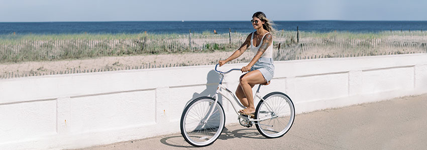Girl riding white Retrospec Chatham Beach Cruiser bike along the beach