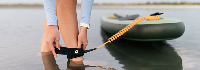 Girl putting on safety leash attached to Retrospec Weekender Inflatable Paddle Board