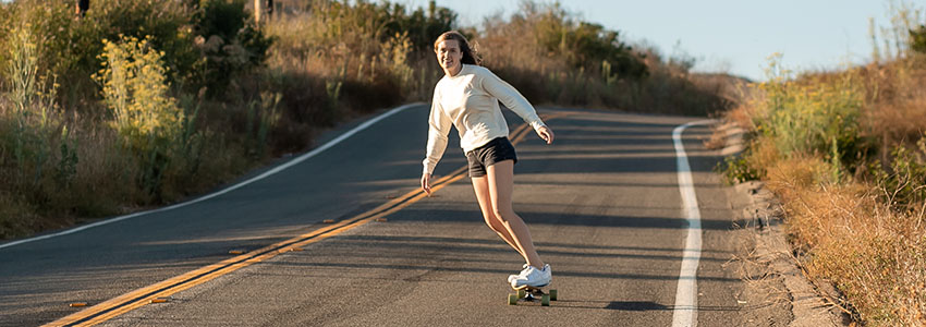 Girl riding Retrospec Zed Longboard down open road