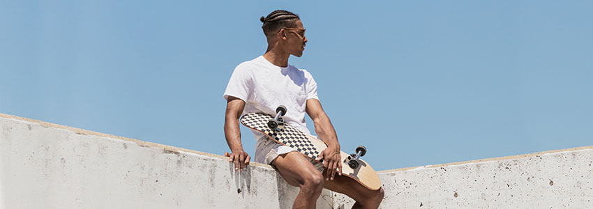 Guy holding Retrospec Alameda Skateboard on top of concrete wall