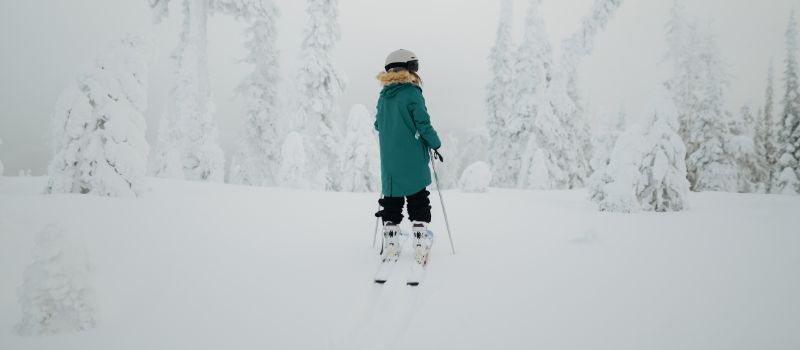 skier in snow wearing blue jacket and Retrospec snow helmet
