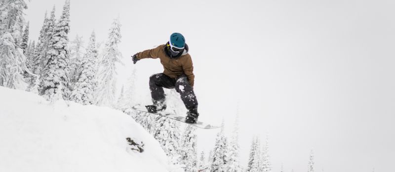 Action shot of snowboarder wearing Retrospec ski helmet and goggles