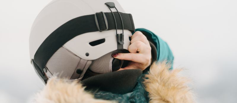Person adjusting the size of their ski helmet using a roller wheel