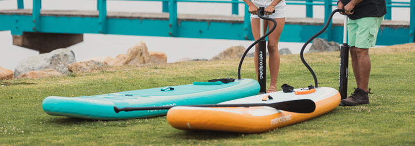 Two people pumping up their inflatable paddle boards