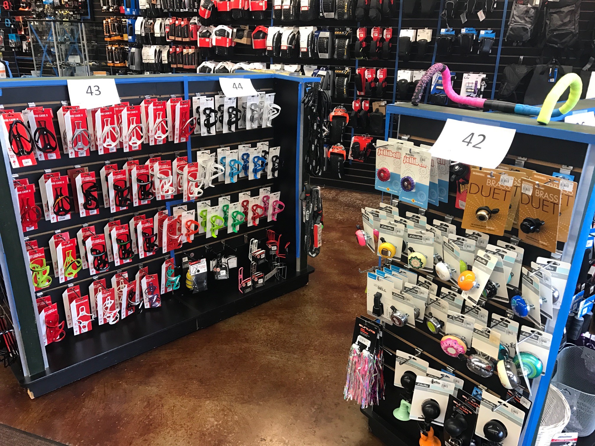Photo of a store with the number 43 above a selection of water bottle cages with red packaging, the number 44 above bottle cages with white packaging.