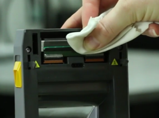 Photo of a hand holding an alcohol wipe cleaning the cutting mechanism of the printer