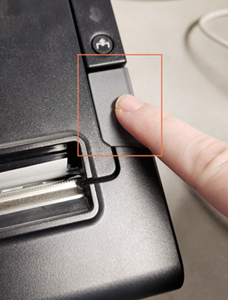 Photo d'un doigt appuyant sur un gros bouton situé sur le côté droit de l'imprimante